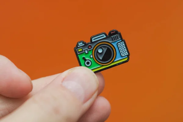 Emaille Broche Camera Hand Oranje Achtergrond — Stockfoto