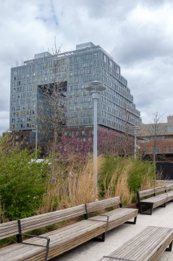 Brooklyn, New York - ABD - 17 Nisan 2021: Arka planda 325 Kent Bulvarı 'ndaki Domino Park' taki bahçelerin ve oturma alanlarının manzarası, lüks bir apartman kompleksi,.