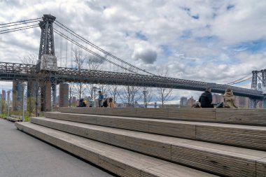 Brooklyn, NY - ABD - 17 Nisan 2021: İnsanlar Domino Park 'ın Rafineri' den el yapımı ahşaptan yapılmış Oturma Basamakları piramidi üzerinde rahatlıyor. Williamsburg 'da East River' da bir halk parkı var..