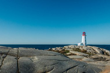 Peggy 'nin Koyu, NS - CA - 29 Sep 2025 Sembolik Peggy' nin Deniz Feneri, berrak bir gökyüzünün altındaki engin, derin, mavi Atlantik Okyanusu 'na bakan büyük bir granit kayanın üzerinde duruyor..