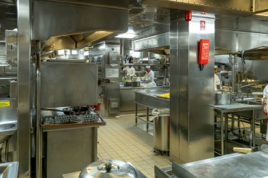 Atlantik Okyanusu - 1 Ekim 2025 Büyük, hareketli profesyonel mutfak birden fazla aşçı paslanmaz çelik ekipman, ticari aletler ve döşeme döşemeleri arasında çalışıyor.