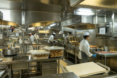 Atlantik Okyanusu - 1 Ekim 2025 Paslanmaz çelik ekipmanlar, ticari aletler ve çeşitli yiyecek maddeleri arasında çalışan birçok aşçıyla dolu yoğun bir mutfak..