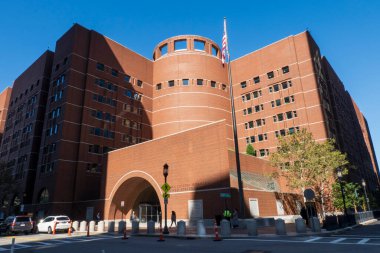 Boston, MA - ABD - 2 Ekim 2025 John Joseph Moakley Birleşik Devletler Adliyesi 'nin alçak açılı bir fotoğrafı, kemerli girişi ve bayrak direği olan büyük, modern tuğla bir bina..