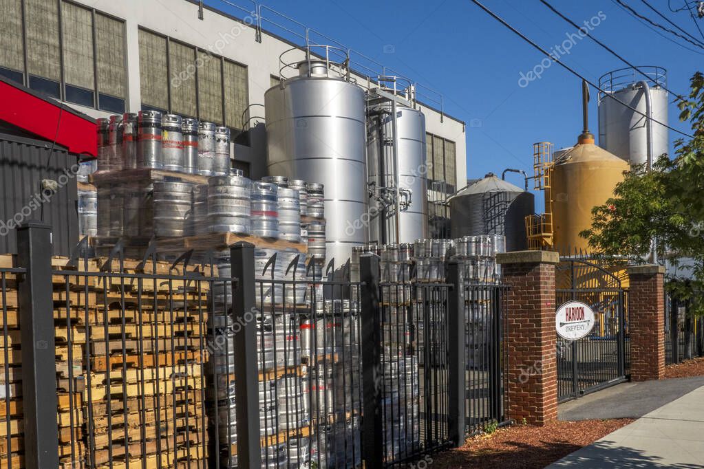 Boston, MA - US - Oct 2, 2025 A black metal gate with a large oval sign for Harpoon Brewery, with the brewery building and kegs visible in the background.