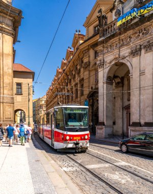Prag, CZ - 4 Haziran 2023 Prag tramvayı güneşli bir caddede tarihi Barok binalarını geçerken kaldırım boyunca yayalar yürüyor..