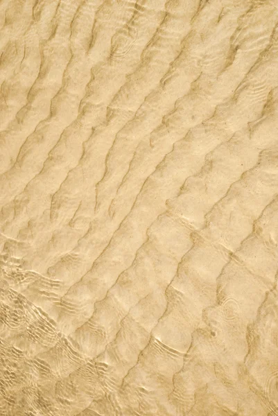 Wasser plätschert über den Sand am Strand — Stockfoto