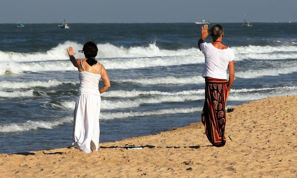 İki kadın pratiği Çigong sahilde Goa, Hindistan