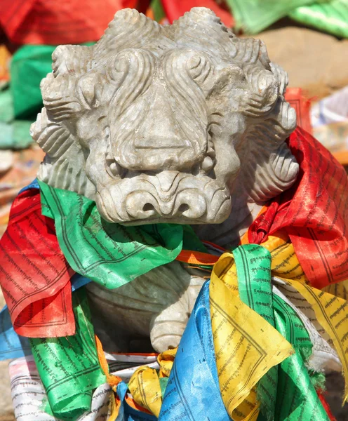 Stone lion figure with traditional buddhist prayer flags in lama — Stock Photo, Image