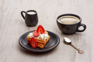 Çilekli Viyana waffle 'ı, krem şanti, bir fincan koyu kahve.