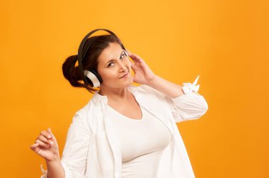 Porno arka planda izole edilmiş kulaklıklarla müzik dinleyen tombul mutlu genç kızın portresi.