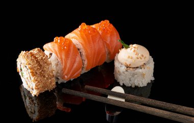 Somon, füme yılan balığı, avokado ve siyah arka planda krem peynirli suşi rulosu (Philadelphia). Suşi menüsü. Japon yemeği..