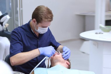 Ortodontist randevusundaki genç bir adam. Ellerinizi koruyucu eldivenlere koyun. Ağız boşluğu için genişletici. Boşluğu kopyala.