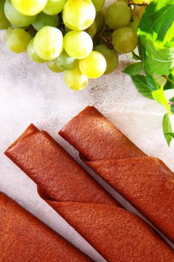 Hafif üzümlerden elde edilen doğal pastil bir tüpe konur. Koruyucu maddeler olmadan doğal ürün. Vejetaryenler için yiyecek. Arka planda dikey fotoğraf. Üst görünüm.