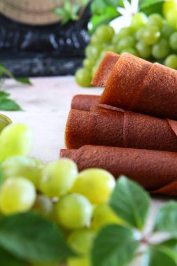 Doğal hafif üzüm şekerlemesi bir tüpe sarılır. Koruyucu maddeler olmadan doğal bioprokanal. Antika pullar. Vejetaryenler için yemek. Odaklanamıyorum. Dikey fotoğraf. Yan görünüm