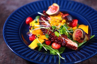 Mangolu ahtapot salatası ve mavi tabakta çilek. İnsansız fotoğraflar. Yemek pişirme konsepti. Üst görünüm.