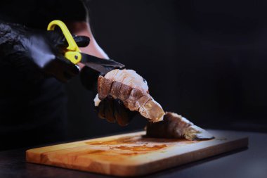 Aşçı ıstakoz kabuğunu makasla keser. Deniz mahsulleri pişiriyorum. Protein yiyeceği. Tanımlanamayan kişi. Ellerinizi koruyucu eldivenlere koyun. Boşluğu kopyala.