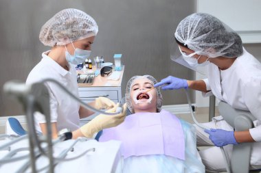 Diş hekimi ve asistanı profesyonel diş temizliği ve ağız temizliği yapar. Dişçi randevusundaki genç bir kız. Dişeti ve sakız hastalıklarının önlenmesi. Ağızda retraktör var..