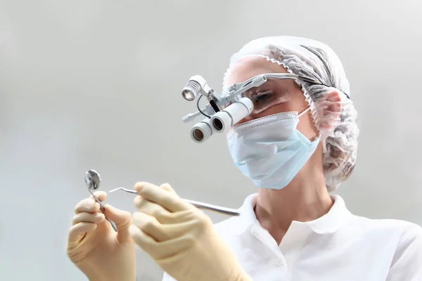 Stomatolog într-un ecran protector și o mască medicală pe față. Ochelari binoculari. Prevenirea cariilor și a bolilor gingivale . — Fotografie, imagine de stoc