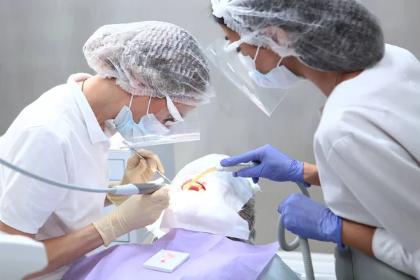 Οδοντίατρος Και Βοηθός Εκτελούν Επαγγελματικό Οδοντιατρικό Καθαρισμό Για Τον Ασθενή — Φωτογραφία Αρχείου