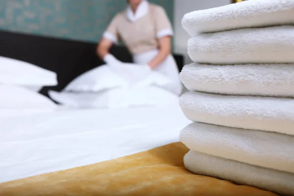 一个穿制服的女佣在一间昂贵的旅馆房间里换床单 这个人注意力不集中 床上干净的毛巾 酒店优质服务的概念 旅馆业复制空间 — 图库照片