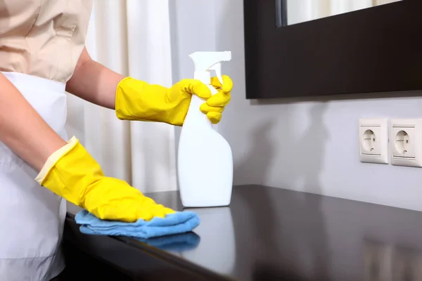 Cleaning in the hotel or in the house. A maid in protective gloves wipes the furniture in a hotel room. an unrecognizable person. Only hand. concept of the hotel business. Copy space.