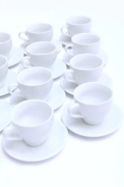 Paires de thé de porcelaine blanche ou de céramique sur la table. Plats pour servir un grand nombre de personnes lors d'une fête ou d'un événement. Vue d'en haut. Photo verticale. — Photo