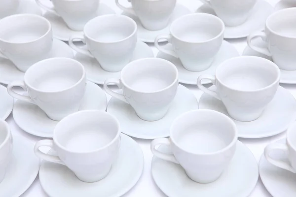 A large number of white porcelain or ceramic tea pairs on the table. Catering or banquet concept. View from above. — Stock Photo, Image