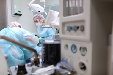 Bir doktor ve bir asistan diş ameliyatı yapıyor. Anestezi altında küçük bir çocuk. Yapay akciğer havalandırma cihazı. Fotoğraf ameliyathanede..