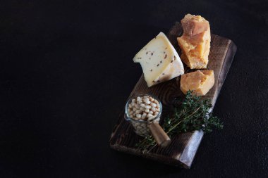 Tahtadaki sert peynirli çam fıstığı parçaları. Siyah arkaplandaki fotoğraf. Üst Manzara. Boşluğu kopyala.