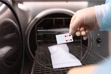 Bir klinik çalışanının elindeki diş aletlerinin sterilizasyonu için bir işaret. Kuru ateş fırını. Modern diş kliniği. Temizlik ve hijyen kavramı. Tanınmayan kişi.