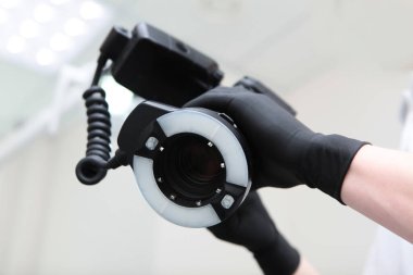 Bir doktorun elinde yüzük flaşı olan kamera. Diş hekimi randevu sırasında kameraya bir fotoğraf çeker. Tanımlanamayan kişi. Sadece koruyucu siyah eldivenli eller. Kopyalama alanı ile