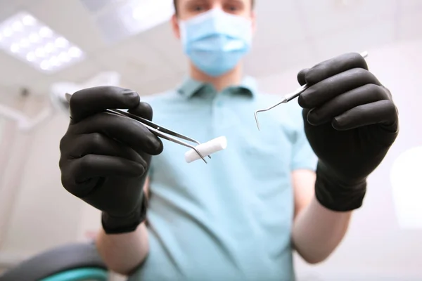 Dentists hands in black latex gloves with medical instruments . Face out of focus. POV. Copy space.