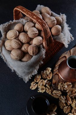 Arka planda sepetteki cevizler. Bakır bir Türk 'te kahve. Ceviz çekirdeği gibi. Tahta tahta. Doğal bir ürün. Dikey fotoğraf. Üst görünüm.