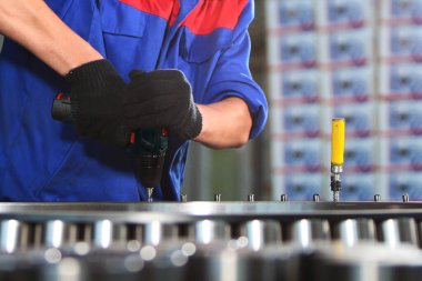 Fabrikada bilyelerin montajı. Ağır endüstri. Geniş çaplı taşıyıcı odak dışı. İşçinin elleri eldivenli. Yatay fotoğraf. Fabrikadaki fotoğraflar..