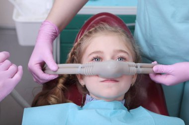 Süt dişlerinin tedavisi. Yüzeysel sakinleştirici. Çocukların dişlerinin azot oksitle tedavi edilmesi. Kliniğin iç kısımlarında fotoğraflar var. Fotoğrafın yatay yönelimi.