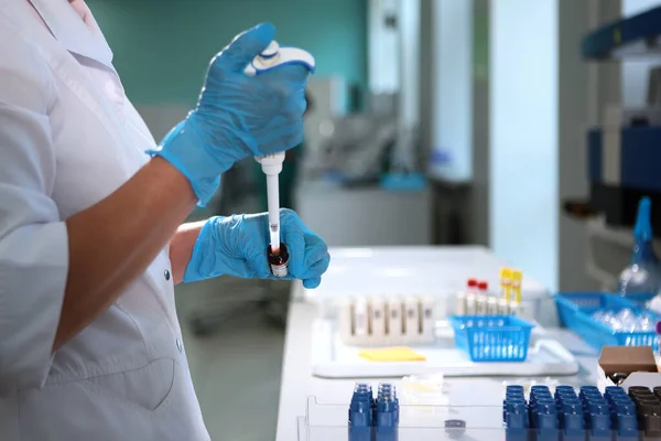 Laboratuvar asistanı araştırma yapıyor ve elinde bir pipet tutuyor. Koruyucu eldivenli laboratuvar asistanının eli. Tıbbi araştırma dışında. Üst görünüm.