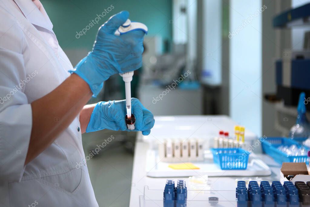 The laboratory assistant conducts research and holds a pipette in his hands. The hand of the laboratory assistant in protective gloves. oncept of medical research. Top view.