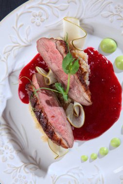 Beyaz tabakta kızılcık soslu ördek göğsü. Makro fotoğraf. Üst Manzara. Dikey fotoğraf. Restoran menüsü konsepti. Mavi arkaplan.