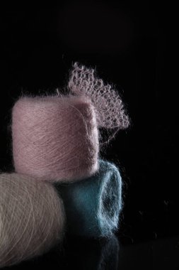 Siyah arka planda çok renkli doğal yün ipliği. Yumuşak tüylü iplik derileri. Hobi kavramı. El yapımı iş. Boş alan. Dikey fotoğraf.