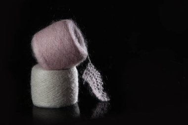 Tangasız pembe ve bej saç teli. Siyah bir arka planda tüylü yün iplikleri. Doğal yün ipliği. Hobi anlayışı. Örgü örme ya da örgü örme tutkusu. El yapımı iş. Serbest alan. Siyah arkaplan..