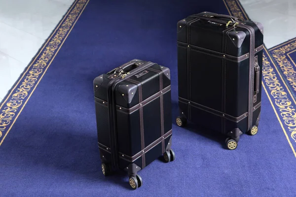 Two suitcases with luggage are on the carpet in the hotel. Comfortable modern luggage. Blue carpet. Top view. The holiday season. Free space.