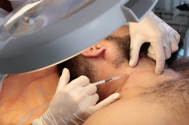 Erkek kozmetolojisi. Kozmetik uzmanı adamdan benleri ayırmadan önce lokal anestezi yapıyor. Güzellik ve sağlık kavramı.