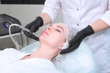 Kozmetikçi randevusunda bir kadın. Donanım kozmetolojisi. Yüz için mikro akım. Cildi taze ve canlı tutma kavramı. Sağlık ve yüz bakımı.