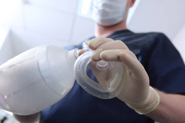 Anesthesiologist holds a spare set of medical equipment for breathing in his hand.Preparation for surgery under general anesthesia.Ambu bag.Artificial ventilation of lungs.Unrecognizable person.Out of focus.