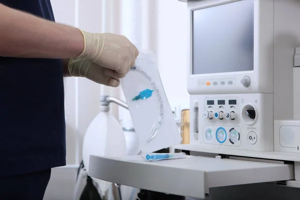 Anesthesiologist opens the package with tracheostomy tube.Preparation for surgery under general anesthesia.A device for artificial ventilation of lungs.An unrecognizable person