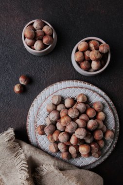 Seramik tabaklarda soyulmamış fındık. Pamuk peçete. Doğal protein. Dikey fotoğraf. Üst görünüm..