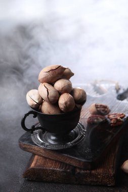 Kabuktaki cevizler metal bardakta. Arka planda duman var. Tahta tahta. Fındıklı. Doğal protein. Dikey fotoğraf. Üst görünüm. Boş alan..