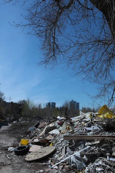 A pile of construction debris on the background of new buildings.Vertical photo without people.The concept of environmental pollution. A copy of the space.