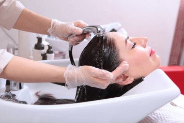 Güzellik salonu müşterisi saçını yıkıyor. Suyun altında uzun saçlar. Saç ve kafa derisi için spa tedavisi. Güzellik kavramı. Berber müşterinin saçını yıkar..