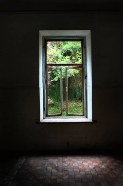 Bahçeye bakan terk edilmiş bir evin penceresini aç. Yıkım belirtileri. Eski bina. Camsız pencere çerçeveleri. İnsansız fotoğraflar. Dikey fotoğraf.